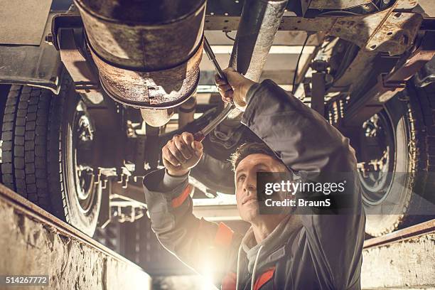 male mechanic using socket wrench while working on chassis. - truck repair stock pictures, royalty-free photos & images