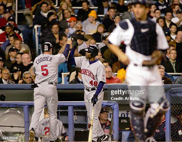 Michael Cuddyer of the Minnesota Twins is congratulated by teammate Torii Hunter after Shannon Stewart hit a single, bringing in the first run of the...