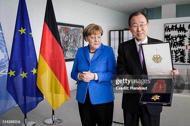 In this handout photo provided by the German Government Press Office , Chancellor Angela Merkel hands over to UN secretary general Ban Ki-moon The...