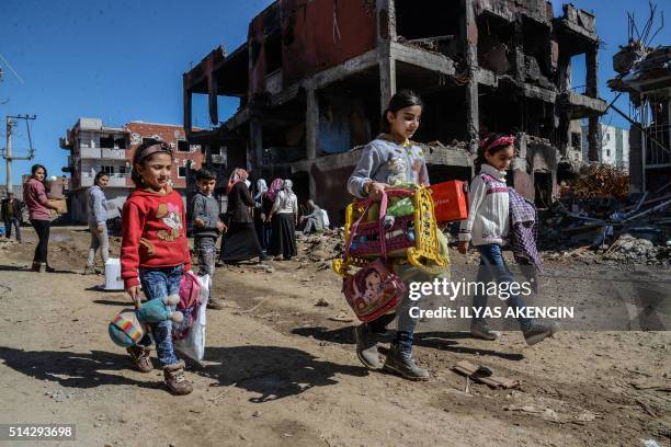 Young girls walk next to ruined houses and shops on March 8, 2016 during International Women's day in Cizre district. Residents of Cizre in...