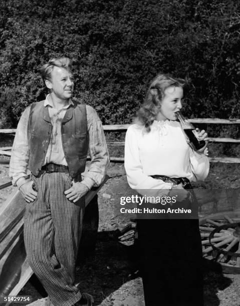 American actress Janet Leigh drinks from a bottle of Pepsi as actor Van Johnson stands next to her with his thumbs in his pockets during a lull in...