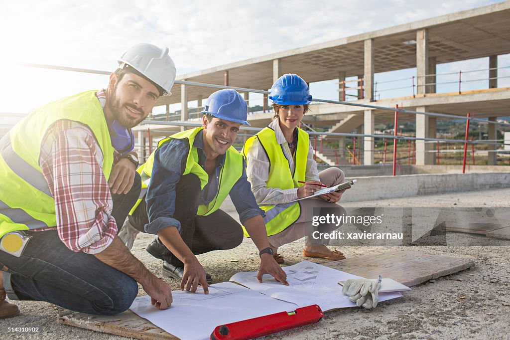 Construction workers and architect looking at blueprints on construction site