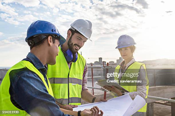 bauarbeitern und architekten, die auf der baustelle pläne liegen vor, - architekt helm plan stock-fotos und bilder