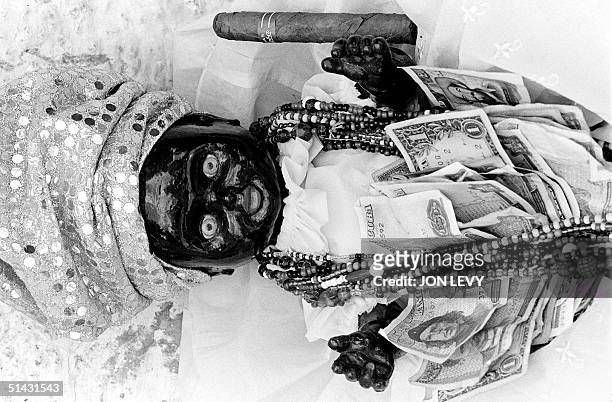 Santeria doll is decorated with offerings of beads, money and cigar at a religious gathering of Catholics near Havana 12 December 1997. The...