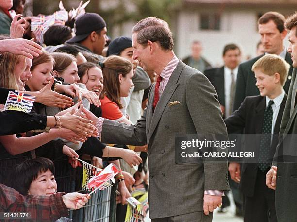 Prince Charles and and his son Prince Harry shake hands with the crowd as they walk into Burnaby High School 24 March in Vancouver. Prince Charles...