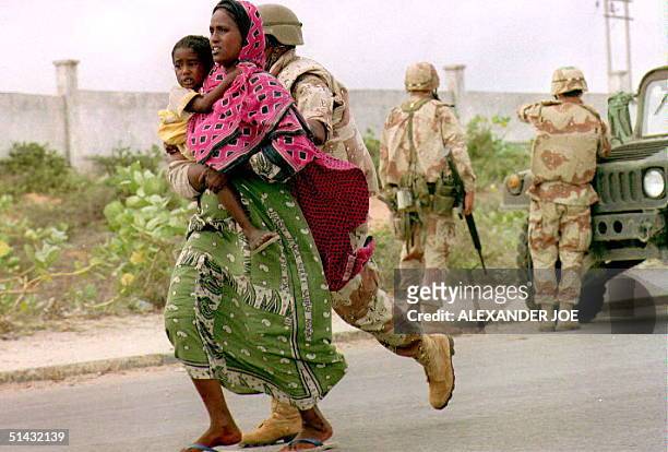Marine escorts a Somali woman and child to safety 12 June 1993 seconds before a large explosion ripped through one of warlord Mohamed Farrah Aidid's...