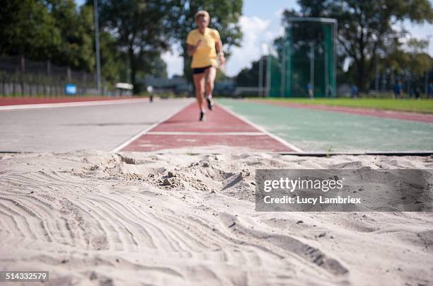 female senior athlete (75) practicing long jump - verspringen stockfoto's en -beelden