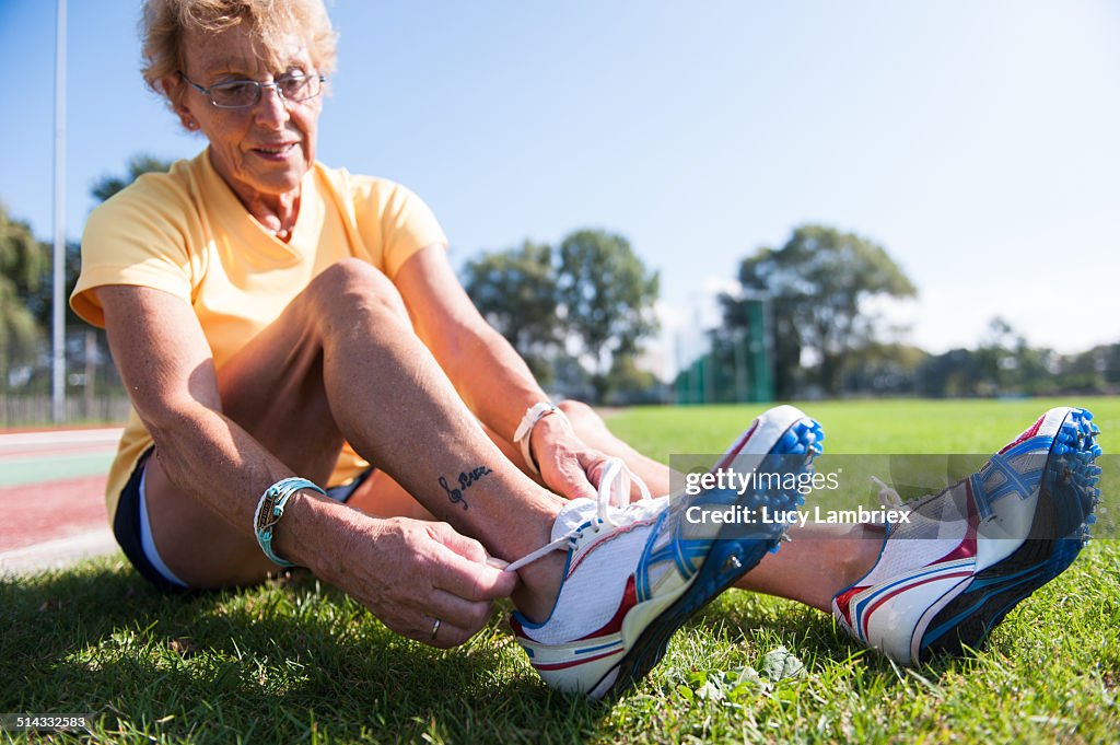 Female senior athlete (75) lacing spiked shoes