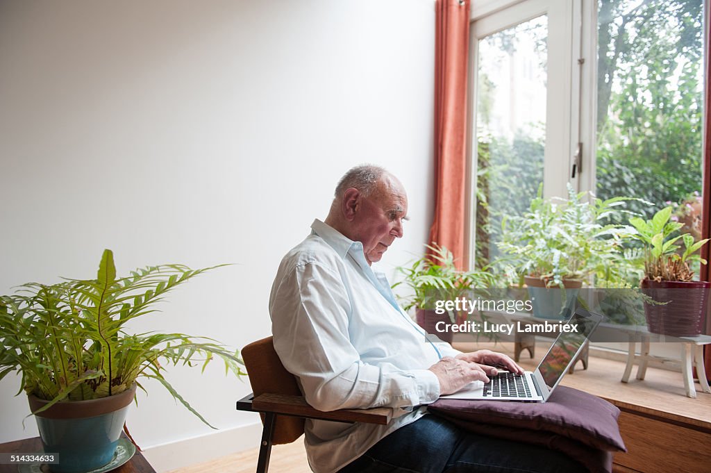 Senior man working on laptop among plants