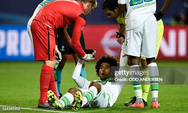 Wolfsburg's Brazilian defender Dante gets help after clashing with Gent's goalkeeper Matz Sels during the second-leg round of 16 UEFA Champions...