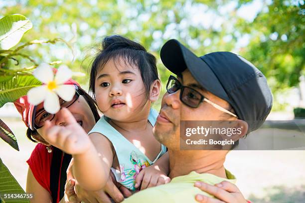 young asian parents show daughter flower outdoors - philippines family stock pictures, royalty-free photos & images