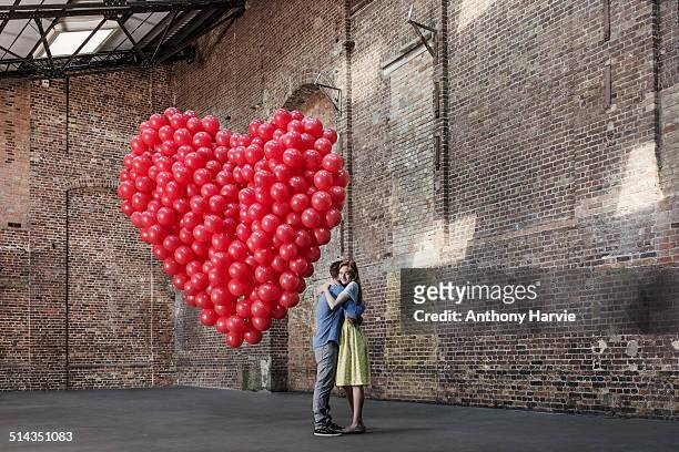 couple in warehouse with heart made of balloons - top secret stockfoto's en -beelden
