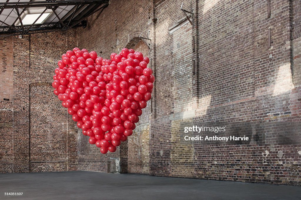 Empty warehouse with red heart made of balloons