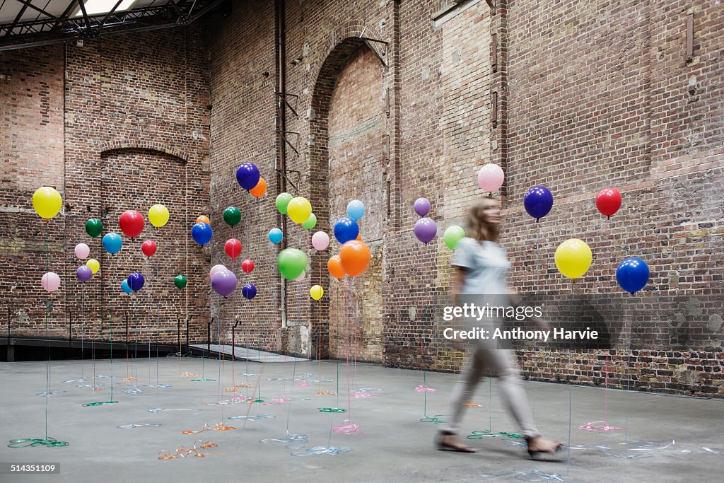 Woman walking in warehouse with colourful balloons