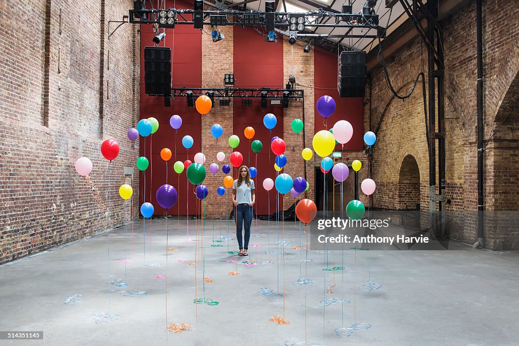 Woman in warehouse with colourful balloons