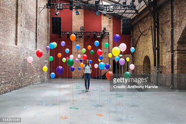 woman in warehouse with colourful balloons - kreativität stock-fotos und bilder