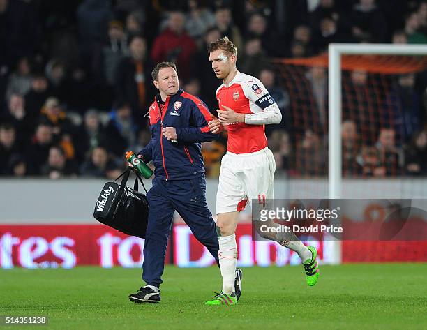 Per Mertesacker of Arsenal with Arsenal physio Colin Lewin during the match between Hull City and Arsenal in the FA Cup 5th round at KC Stadium on...