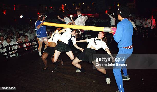 Revellers limbo dance under a pole during a SchoolDisco.com club night at London's Hammersmith Palais nightclub on July 3, 2004 in London. Attendees...