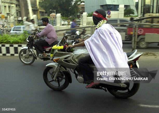 Indian magician Akash Gupta rides his motorcycle blindfold along a street in Madras 07 October 2004. Gupta together with unseen fellow magician Kumar...
