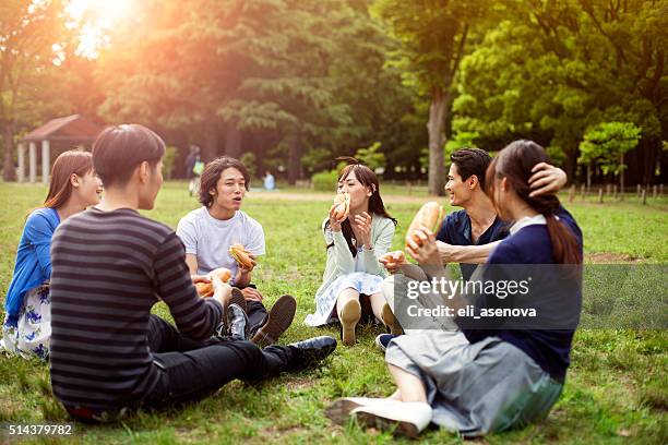 happy group of japanese friends eat in the park, tokyo - 日本食 個照片及圖片檔