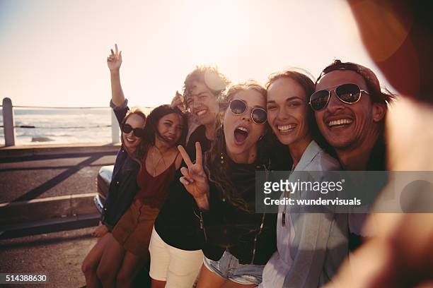 hipster teen friends taking a selfie outdoors at the beach - homesick vacation stock pictures, royalty-free photos & images