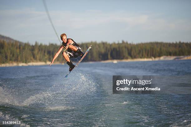 young man in mid-air jump while wake boarding - wakeboarding stock pictures, royalty-free photos & images