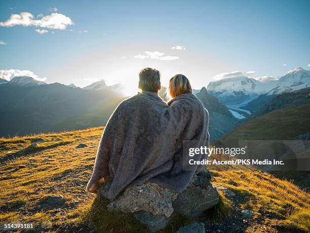 couple huddle in blanket, watch mountain sunrise - ehepaar stock-fotos und bilder