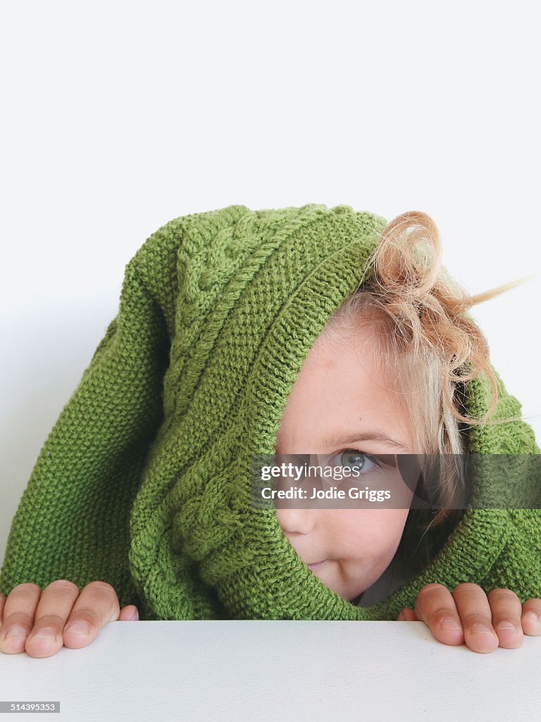 Child peeking over bench with jumper over head