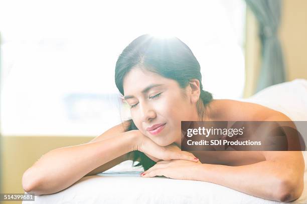 beautiful spa customer relaxing on massage table during treatment - massage table stock pictures, royalty-free photos & images
