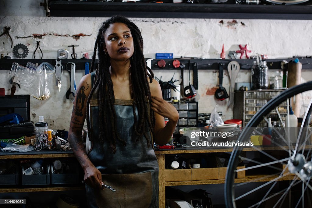 Candid portrait of afro-american bicycle mechanic standing in he