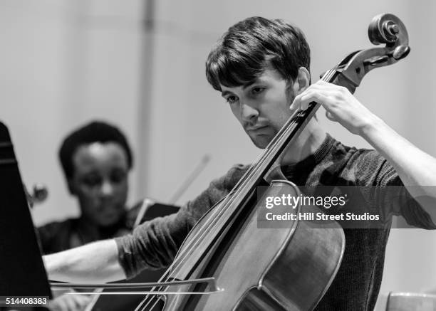 caucasian student playing cello in college orchestra - orchestra rehearsal stock pictures, royalty-free photos & images