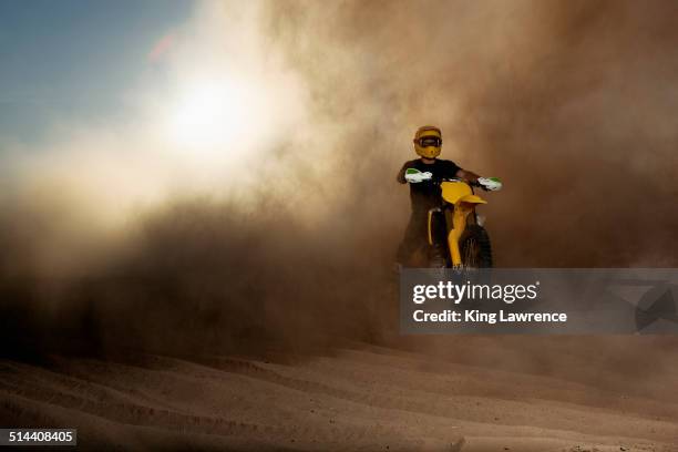 caucasian man riding dirt bike in dust cloud - dirt bike stock pictures, royalty-free photos & images