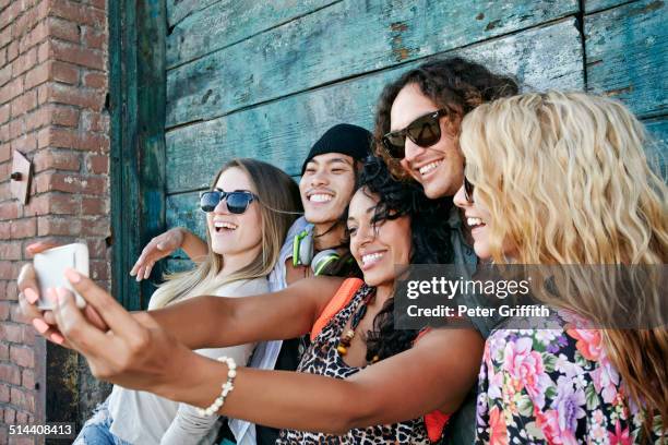 friends taking cell phone picture together on city street - girlfriend fotos stockfoto's en -beelden