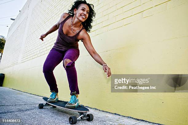 hispanic woman riding skateboard on city street - a la moda stock pictures, royalty-free photos & images