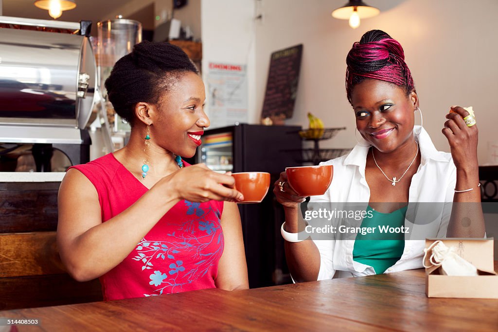 Women toasting each other with coffee in cafe