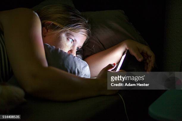 caucasian woman using cell phone in bed - verslaving stockfoto's en -beelden