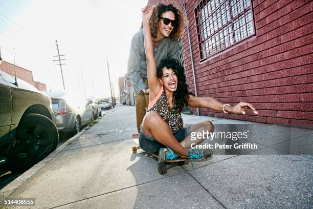 couple riding skateboard on city street - action foto sport fotografías e imágenes de stock