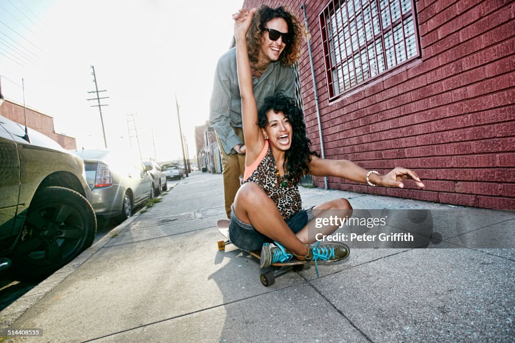 Couple riding skateboard on city street