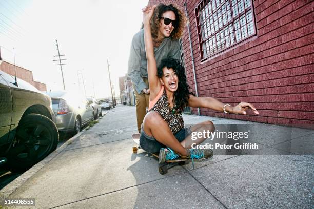 couple riding skateboard on city street - funky friends stock pictures, royalty-free photos & images