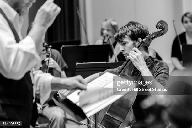 caucasian student playing cello in college orchestra - dirigent orchester stock-fotos und bilder