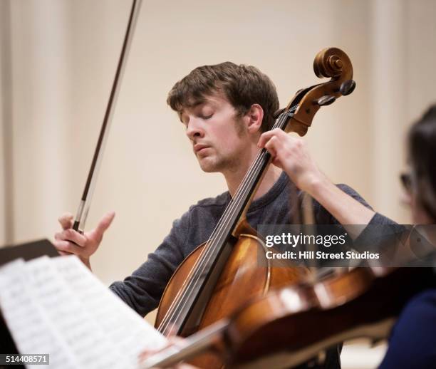 caucasian student playing cello in string quartet - plucking an instrument - fotografias e filmes do acervo