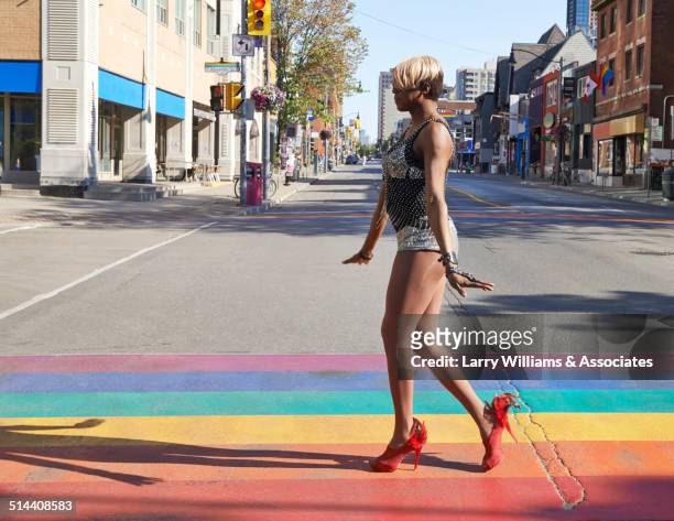 black drag queen walking on rainbow pavement on city street, toronto, ontario, canada - dragqueen stock-fotos und bilder