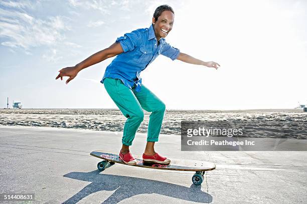 older black woman skateboarding by beach - mature woman beauty arm stockfoto's en -beelden