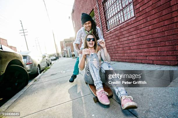 couple riding skateboard on city street - couple skating stock pictures, royalty-free photos & images