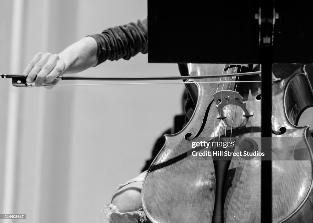 Caucasian student playing cello in college orchestra