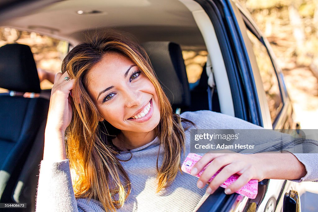 Mixed race woman holding cell phone in car