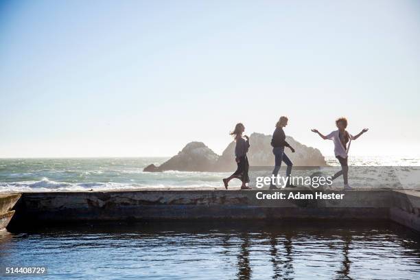 silhouette of women walking on pool on coastline - walking side view stock-fotos und bilder