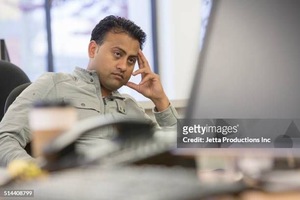 asian businessman thinking at desk in office - reizen stock-fotos und bilder