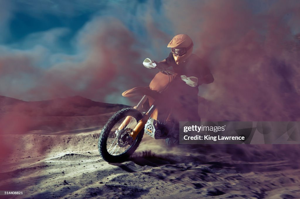 Caucasian man riding dirt bike in dust cloud
