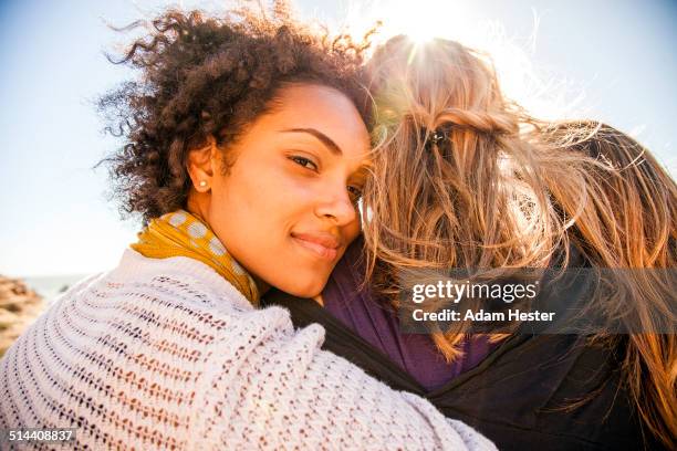 women standing together outdoors - embracing foto e immagini stock